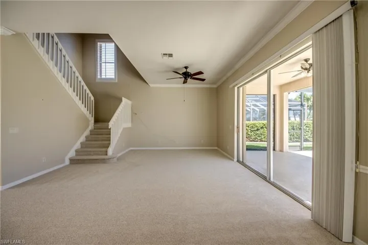 Unfurnished living room featuring light colored carpet, a ceiling fan, and crown molding