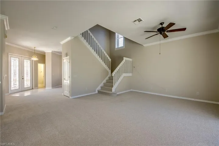 Unfurnished living room with ornamental molding, light carpet, french doors, a ceiling fan, and healthy amount of natural light