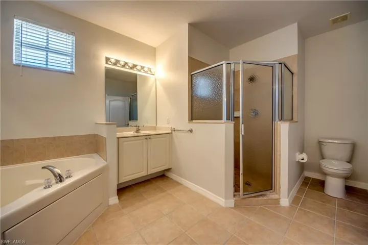 Full bathroom with a stall shower, a bath, vanity, and light tile patterned floors