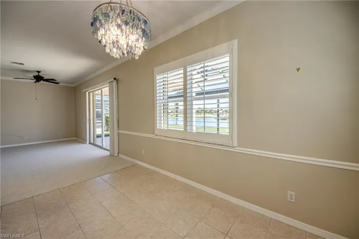 Empty room with ceiling fan, ornamental molding, suspended lighting, light tile patterned floors, and light colored carpet