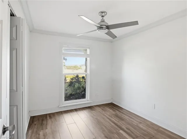 Empty room featuring crown molding, wood finished floors, and ceiling fan