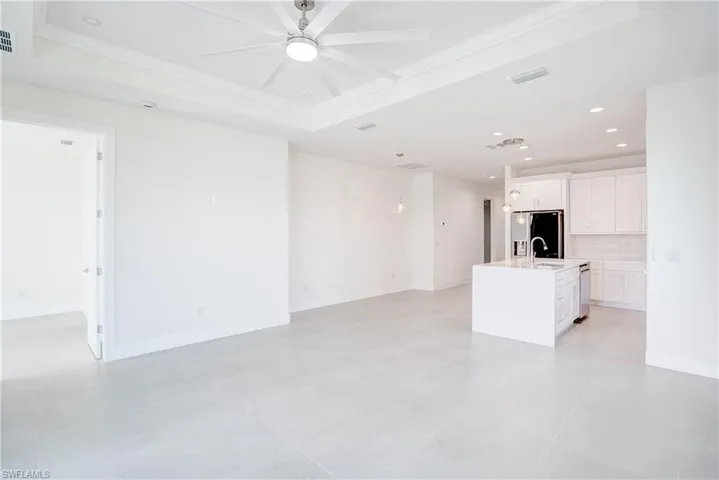 Unfurnished living room with a ceiling fan, recessed lighting, and a tray ceiling