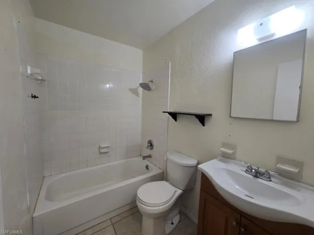 Bathroom with vanity,  shower combination, a textured wall, and light tile patterned floors