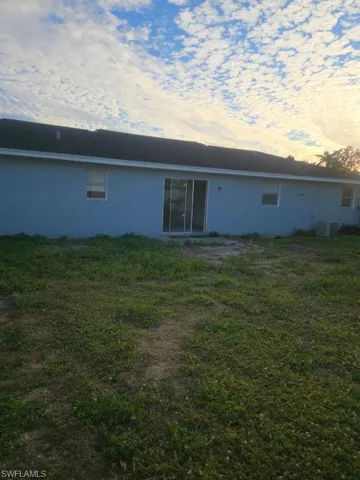 Back of property with a yard and stucco siding