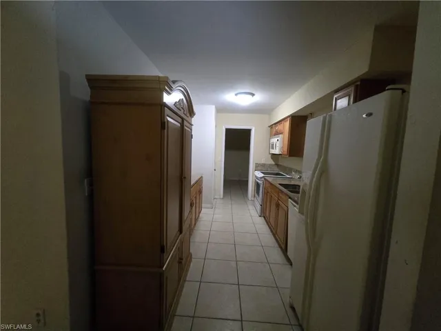 Kitchen featuring white appliances, light tile patterned floors, and wood finish cabinets