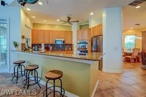 Kitchen with a peninsula, light tile patterned floors, a breakfast bar area, stainless steel appliances, and recessed lighting