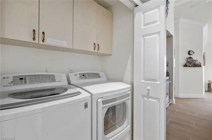 Laundry area featuring washer and dryer, cabinets, and light wood-type flooring