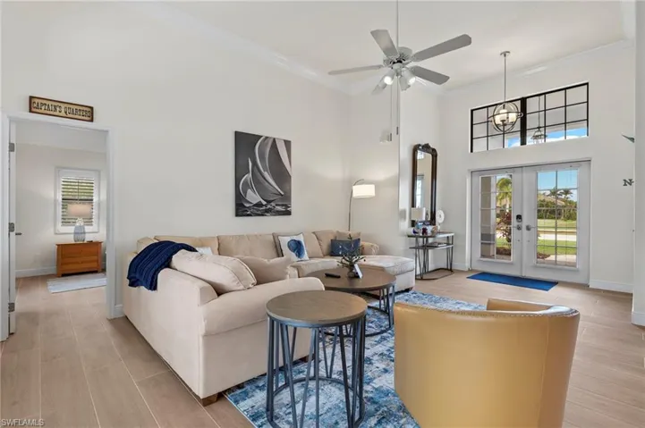 Living room featuring ceiling fan, french doors, a high ceiling, and ornamental molding