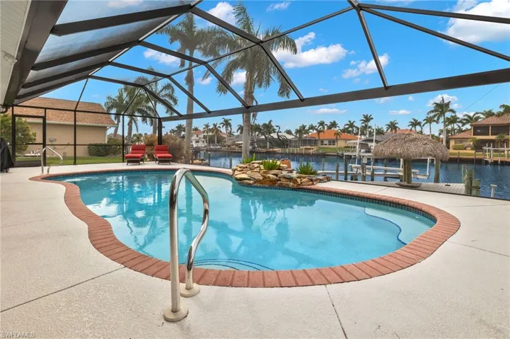 View of pool featuring a lanai, a water view, a boat dock, and a patio