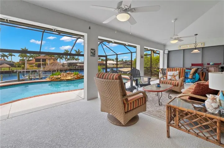 Carpeted living room featuring vaulted ceiling, a water view, a healthy amount of sunlight, and ceiling fan