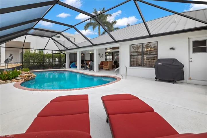 View of pool with glass enclosure, a patio area, ceiling fan, and area for grilling
