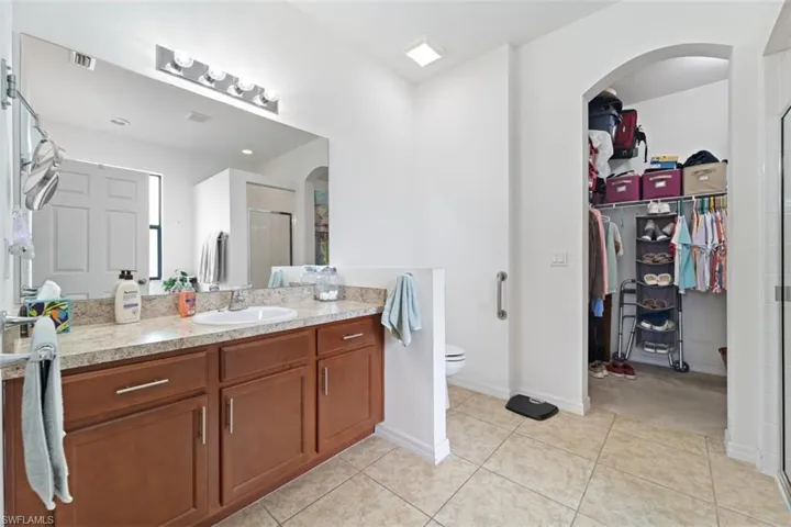 Bathroom featuring vanity, a stall shower, light tile patterned floors, and a spacious closet