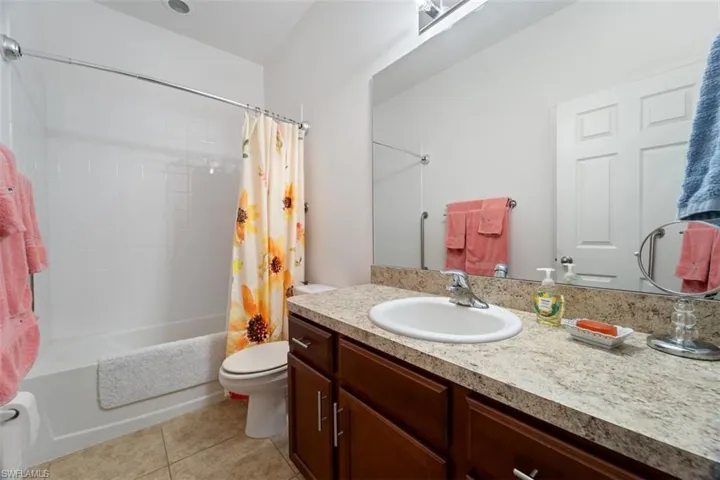 Full bath with shower / bath combo with shower curtain, light tile patterned floors, and vanity