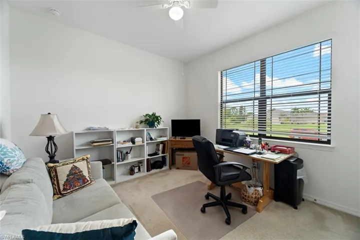 Home office with light carpet and ceiling fan
