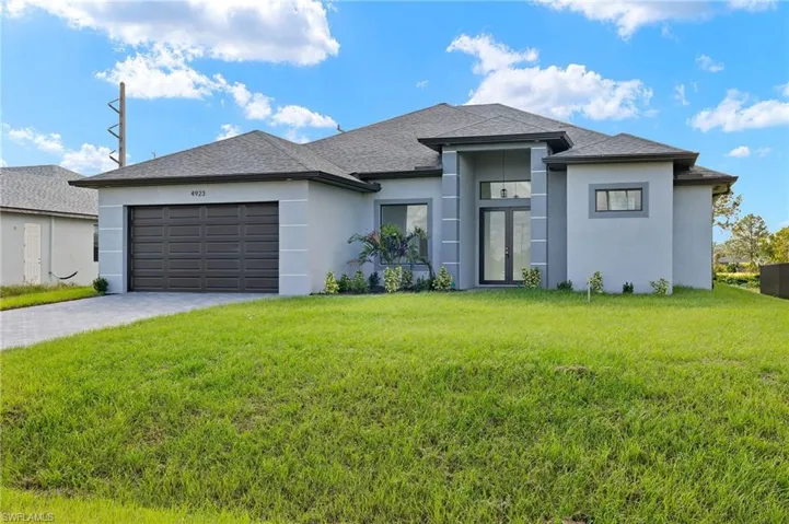 View of front facade featuring a garage and a front yard