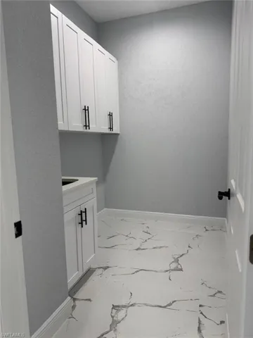 Laundry area with baseboards and light marble finish floors