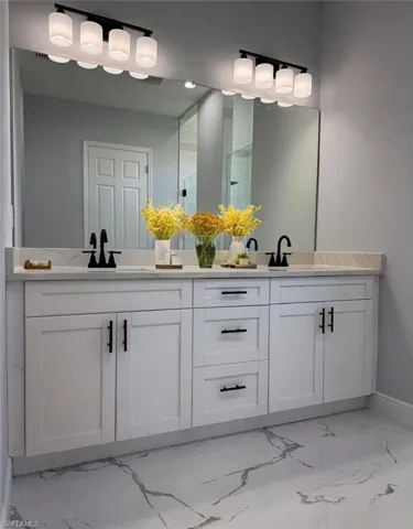 Bathroom with marble look tiles, double vanity, and baseboards