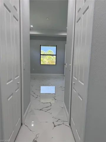 Hall featuring baseboards, marble tiled flooring, and recessed lighting