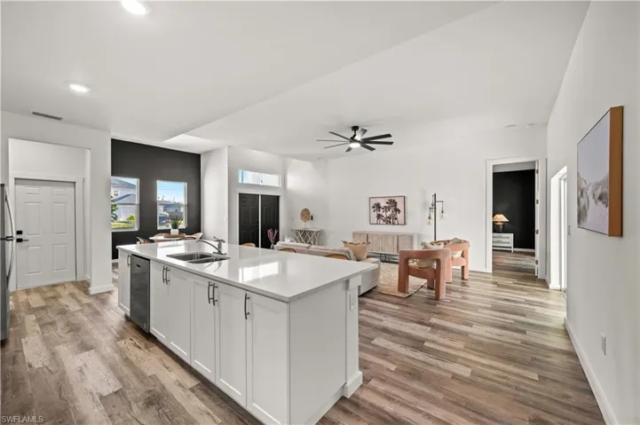Kitchen featuring stainless steel dishwasher, a center island with sink, hardwood / wood-style flooring, and sink