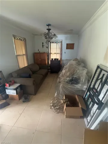 Living area featuring an inviting chandelier, tile patterned floors, and ornamental molding
