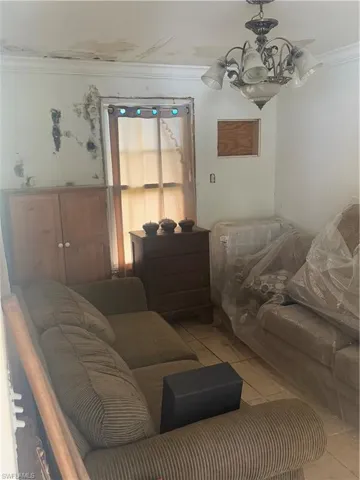 Living area featuring an inviting chandelier, light tile patterned flooring, and crown molding