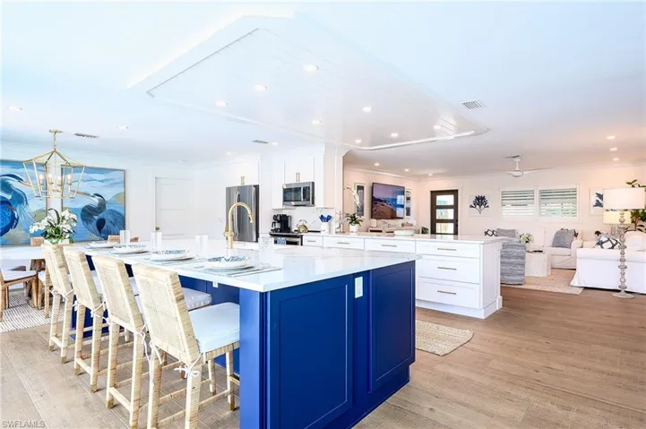 Kitchen with appliances with stainless steel finishes, light wood-type flooring, white cabinetry, and a large island