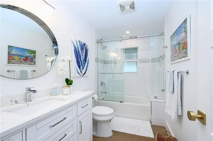 Full bathroom featuring bath / shower combo with glass door, vanity, and toilet