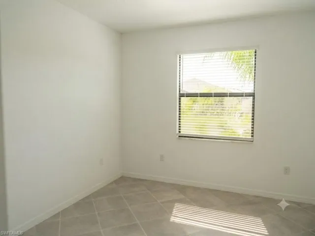 Neutral white walls and tiled flooring featuring a single window with blinds