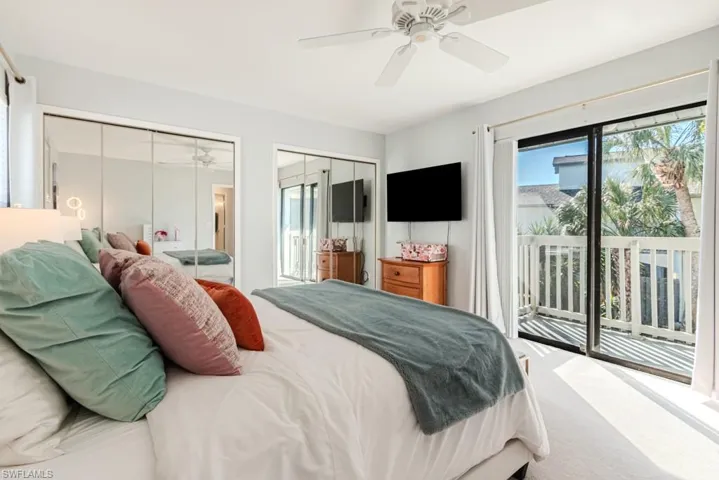 Carpeted bedroom with ceiling fan, access to outside, and multiple closets