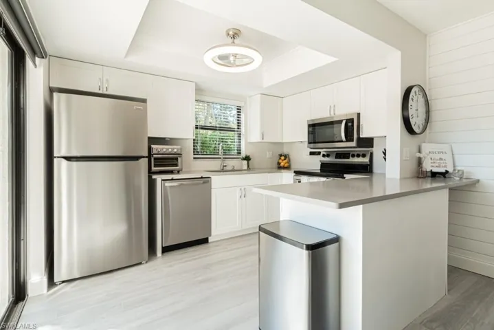 Kitchen with white cabinets, kitchen peninsula, sink, and appliances with stainless steel finishes