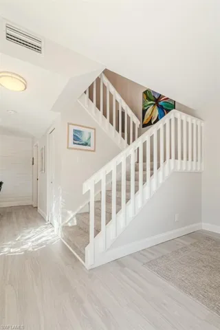 Stairs featuring hardwood / wood-style floors and vaulted ceiling
