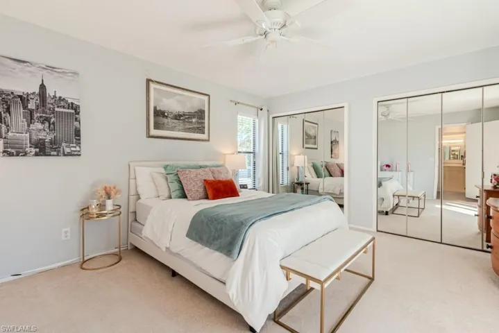 Bedroom with ceiling fan, light colored carpet, and two closets