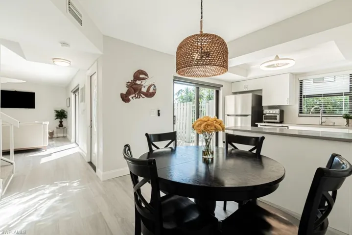 Dining room with a raised ceiling, light hardwood / wood-style flooring, a wealth of natural light, and sink
