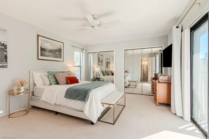 Bedroom featuring light carpet, two closets, and ceiling fan