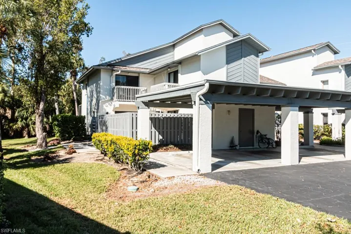 Back of property featuring a lawn, a balcony, and a carport