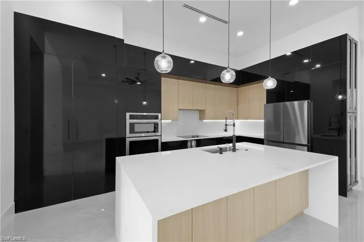 Kitchen with light brown cabinetry, sink, a center island with sink, and stainless steel appliances