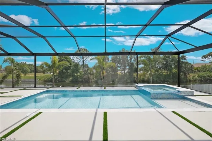 View of swimming pool with a patio area, an in ground hot tub, and a lanai