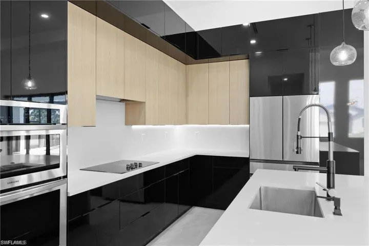 Kitchen featuring appliances with stainless steel finishes, sink, light brown cabinetry, and hanging light fixtures