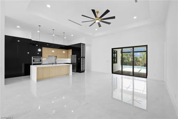 Kitchen with a kitchen island with sink, light tile floors, and a raised ceiling