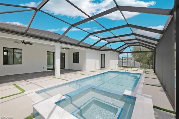 View of swimming pool with glass enclosure, an in ground hot tub, a patio area, and ceiling fan