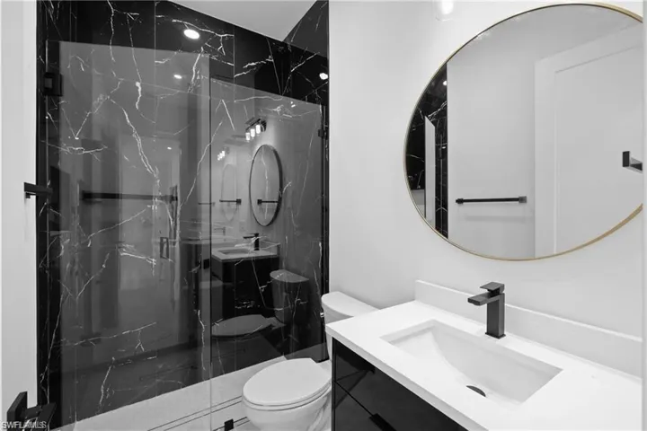 Bathroom featuring a shower with door, vanity, and toilet