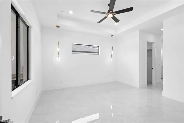 Spare room featuring tile flooring, ceiling fan, and a raised ceiling