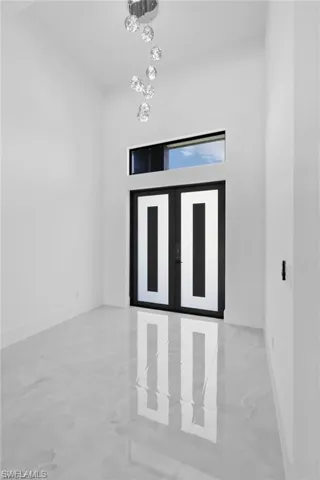 Unfurnished room featuring light tile flooring and a chandelier
