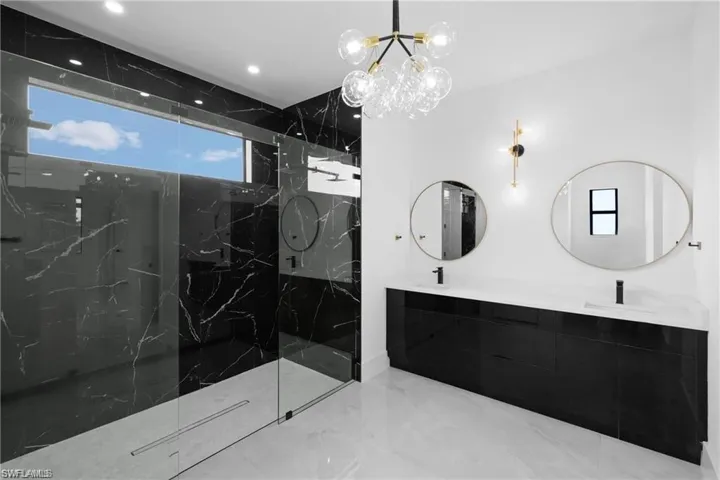 Bathroom with tiled shower, tile floors, and a notable chandelier