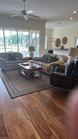 Living room with molding, ceiling fan, and wood finished floors
