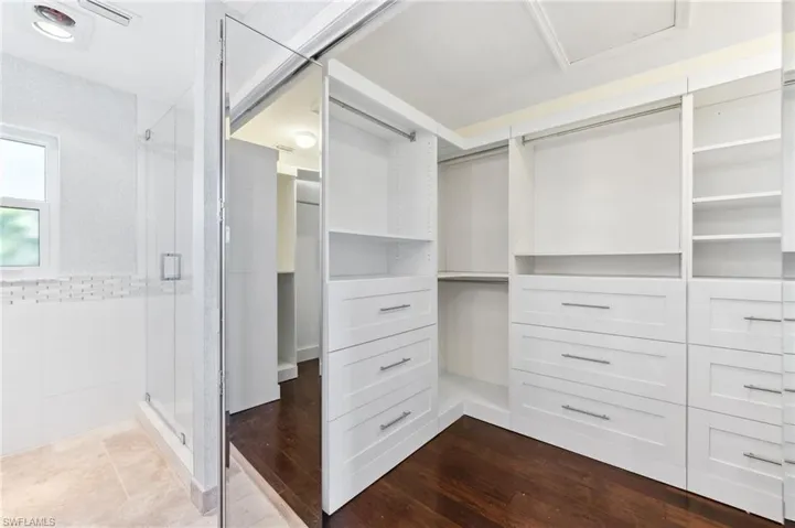 Walk in closet with dark wood finished floors