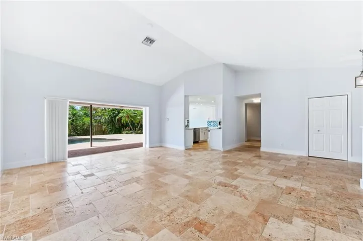 Unfurnished living room featuring visible vents, baseboards, high vaulted ceiling, and stone tile flooring