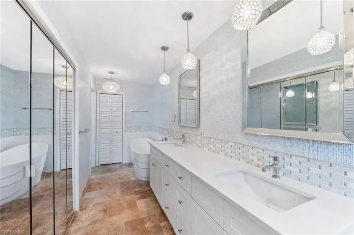 Full bathroom with a sink, stone finish flooring, a soaking tub, and double vanity