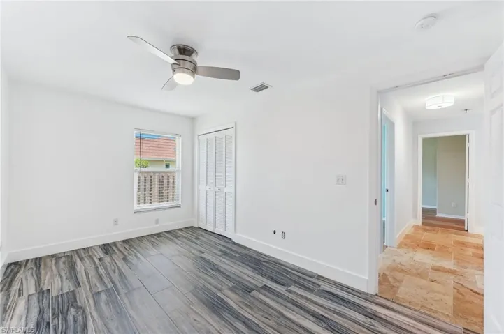 Unfurnished room with wood finished floors, visible vents, baseboards, and ceiling fan