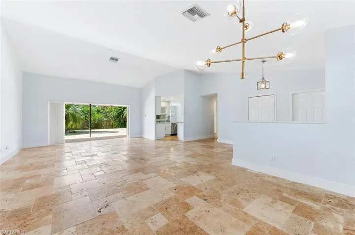 Unfurnished living room with visible vents, baseboards, an inviting chandelier, and stone tile floors
